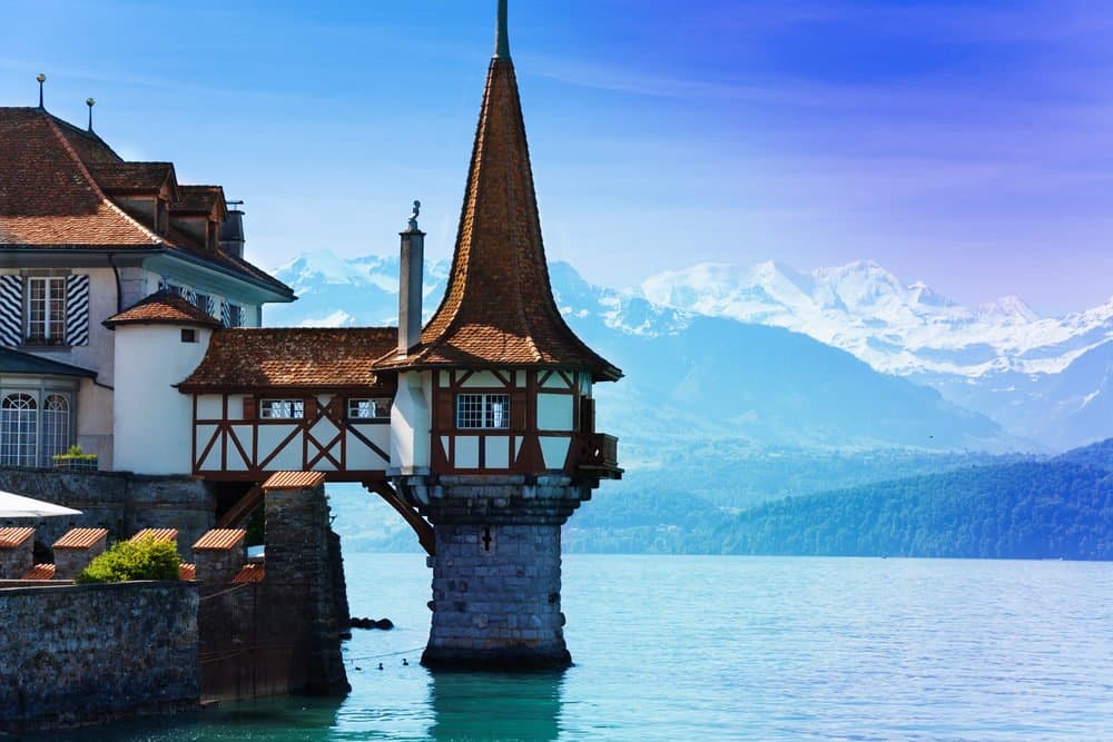 Beautiful little tower of Oberhofen castle in the Thun lake with mountains on background in Switzerland, near Bern