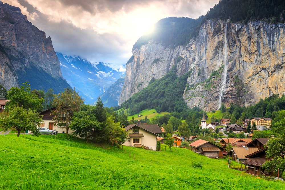 Green fields and famous touristic town with high waterfall in background,Lauterbrunnen,Bernese Oberland,Switzerland,Europe