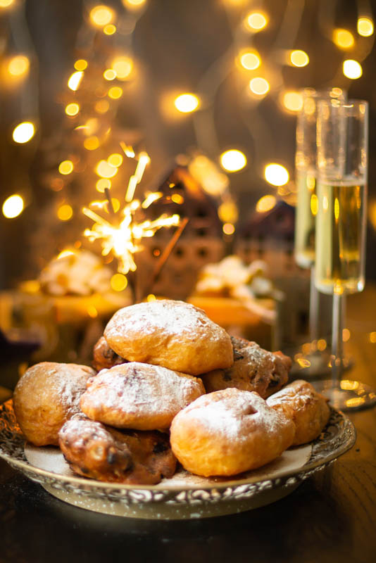 Oliebollen traditional Dutch New Year's Eve pastry dusted with powder sugar served with champagne